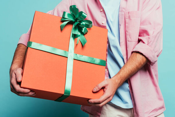 cropped view of man holding big gift box on blue