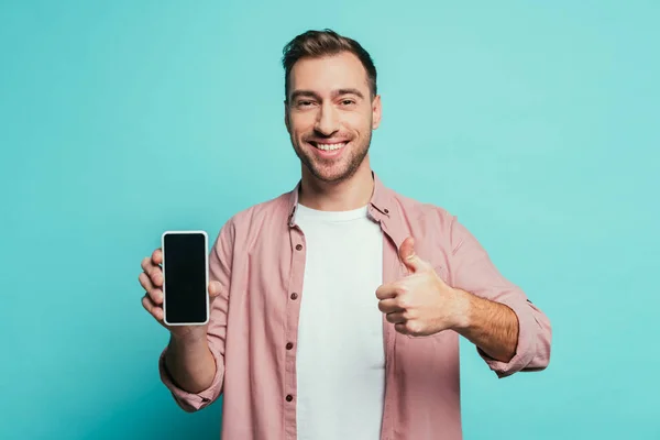 Wesoły Mężczyzna Pokazuje Kciuk Górę Smartfon Pustym Ekranem Odizolowany Niebiesko — Zdjęcie stockowe