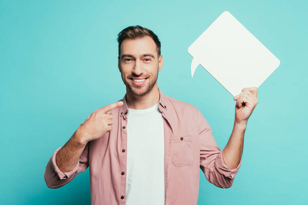 happy man pointing at empty speech bubble, isolated on blue