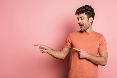Pembe arka plana bakarken parmaklarıyla işaret eden genç adam hayrete düştü.