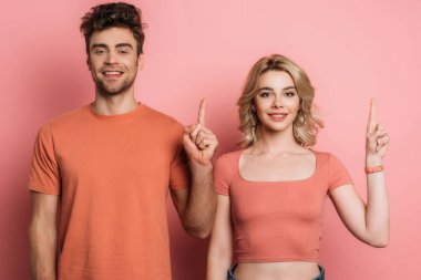 pozitif erkek ve kadın pembe arka plandaki kameraya bakarken fikir belirtileri gösteriyor