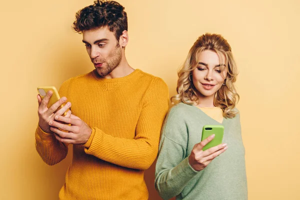 Positive Attentive Couple Chatting Smartphones Yellow Background — Stock Photo, Image