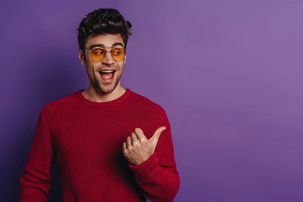 Cheerful Young Man Pointing Thumb Looking Away Purple Background — Stock Photo, Image