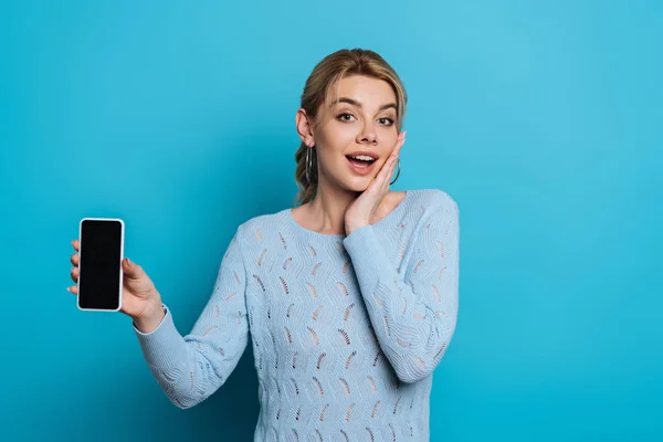 Surprised Girl Touching Face While Showing Smartphone Blank Screen Blue — Stock Photo, Image