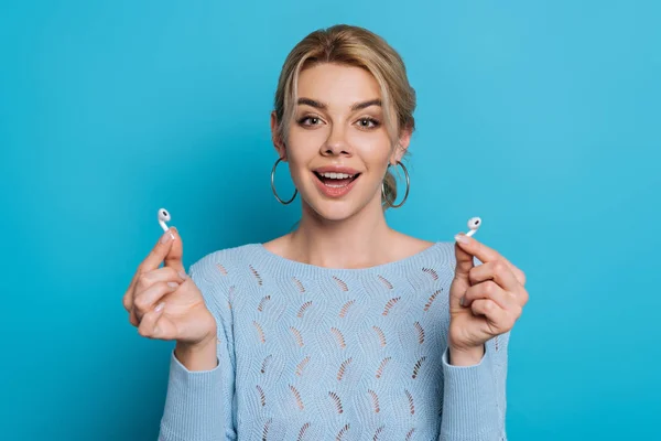 Happy Girl Showing Wireless Earphones While Smiling Camera Blue Background — Stock Photo, Image