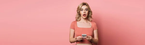 Panoramatický Záběr Šokované Dívky Při Pohledu Kameru Zatímco Chatování Smartphone — Stock fotografie