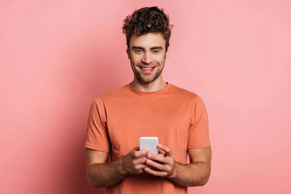 Positive Young Man Smiling Camera While Chatting Smartphone Pink Background — Stock Photo, Image