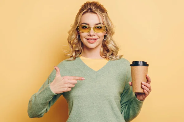 Menina Bonita Elegante Apontando Com Dedo Para Copo Descartável Enquanto — Fotografia de Stock