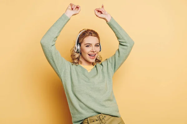 Cheerful Girl Listening Music Wireless Headphones Dancing Looking Camera Yellow — 스톡 사진