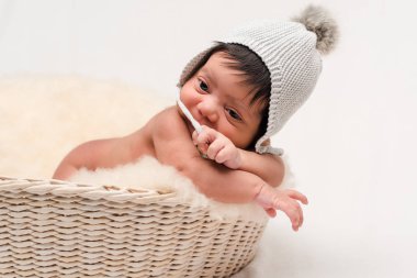 Sevimli yeni doğmuş melez bebek örgü örülmüş şapkaya dokunuyor