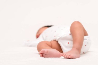 selective focus of cute newborn in baby romper and socks lying on white  clipart