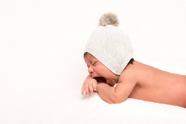 adorable mixed race baby in knitted hat yawning isolated on white 