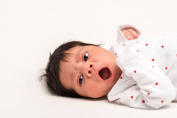 adorable mixed race newborn in baby romper yawning isolated on white 