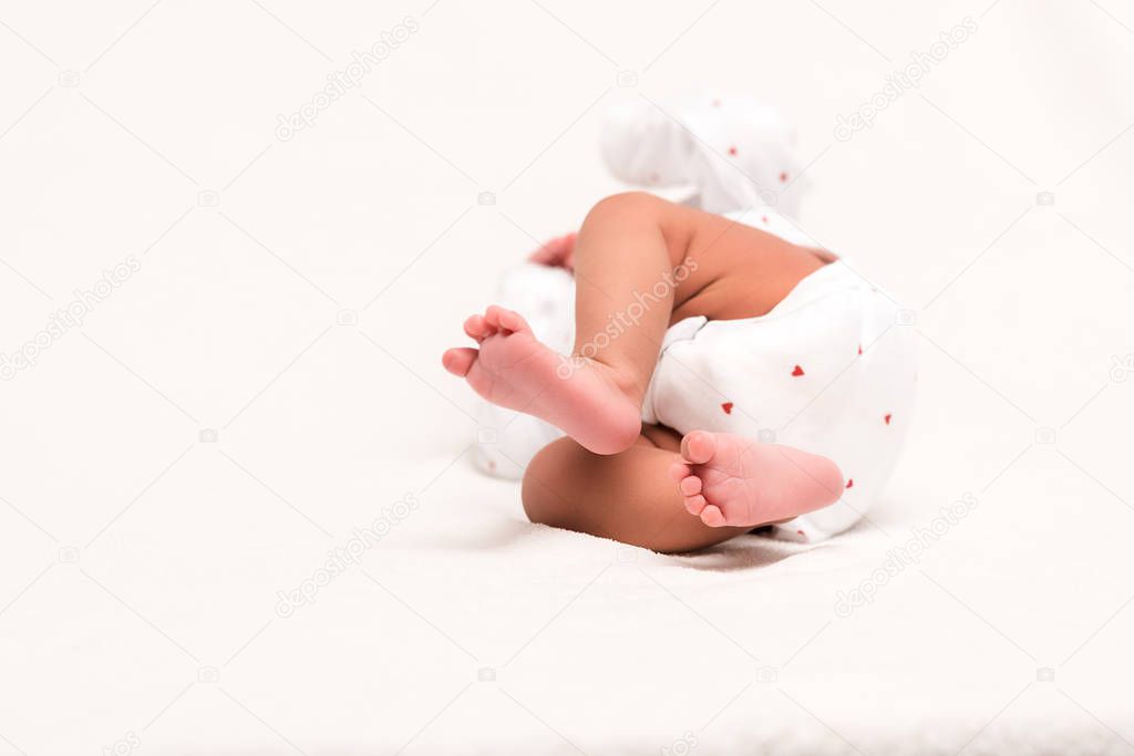 cute newborn in baby romper lying on white 