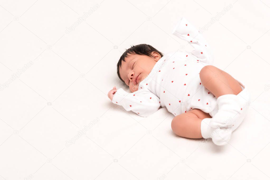 cute bi-racial newborn in baby romper and socks sleeping on white 