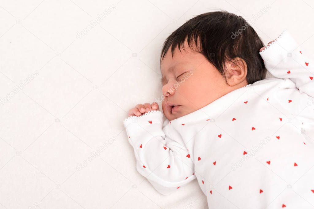 top view of adorable bi-racial newborn in baby romper sleeping isolated on white 
