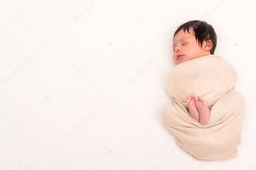 top view of bi-racial baby wrapped in blanket sleeping isolated on white 