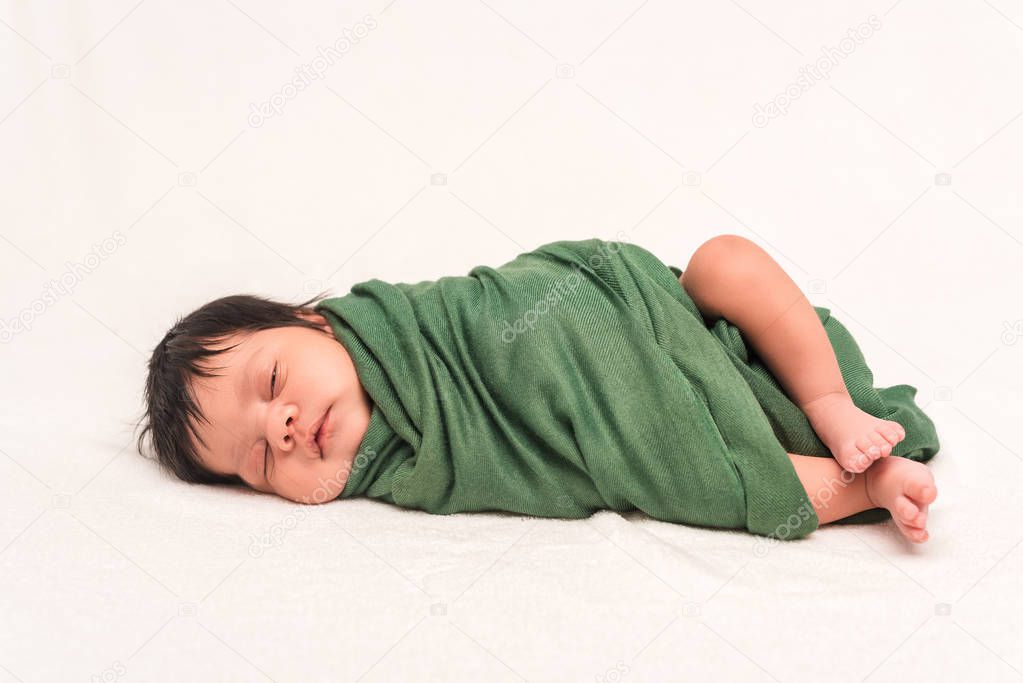 adorable bi-racial baby wrapped in green blanket sleeping isolated on white 