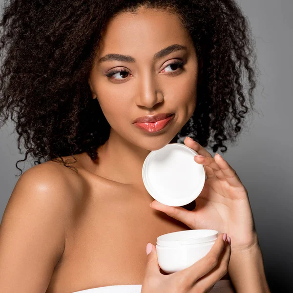 Atractiva Chica Afroamericana Sosteniendo Contenedor Plástico Con Crema Cosmética Aislado — Foto de Stock