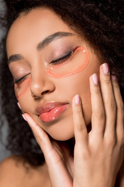 african american girl with closed eyes with hydrogel eye patches, on grey