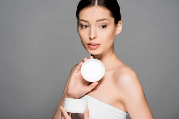 Atractiva Chica Sosteniendo Contenedor Plástico Con Crema Facial Aislado Gris — Foto de Stock