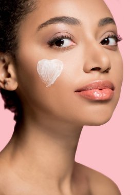 portrait of african american girl with heart of cream of cheek, isolated on pink   clipart