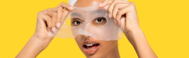 Kafasında havlu olan, sarı üzerine izole edilmiş hidrojel maske takan afro-amerikan bir kızın panoramik çekimi.