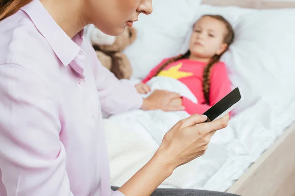 Cropped View Mother Using Smartphone Ill Daughter Bed — Stock Photo, Image