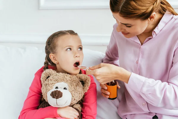 Mother Giving Syrup Ill Daughter Teddy Bear — Stock Photo, Image