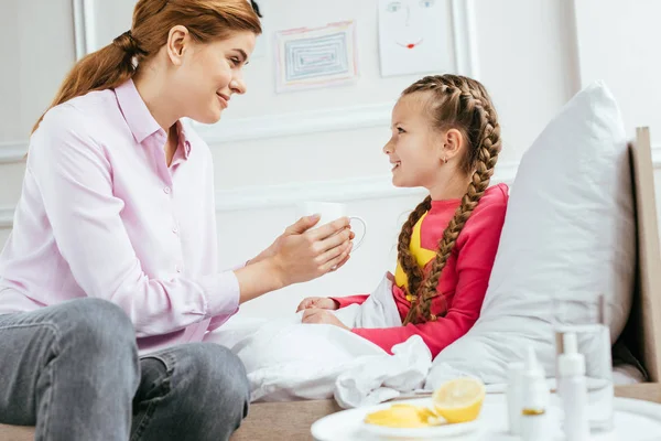 Smiling Mother Giving Hot Drink Ill Daughter Bed Medicines — Stock Photo, Image