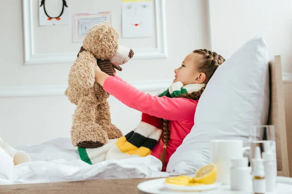 Happy Ill Kid Scarf Holding Teddy Bear Bed Medicines — Stock Photo, Image