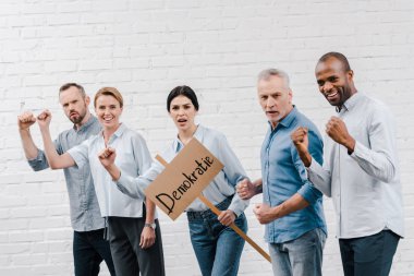 Bir grup çok kültürlü kadın ellerinde demokratik harflerle pankart tutuyorlar. 
