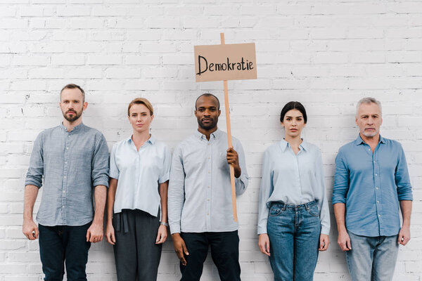 group of people standing near african american man holding placard with demokratie lettering 