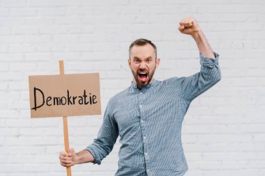 Duygusal vatandaşın elinde bir pankart var. Duvarda yazılı ve çığlık çığlığa bir demokrat var. 