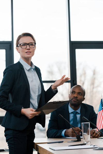selective focus of attractive diplomat gesturing while talking near african american representative 