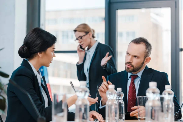 Selective Focus Diplomats Talking Gesturing Businesswoman Using Smartphone — Stock Photo, Image