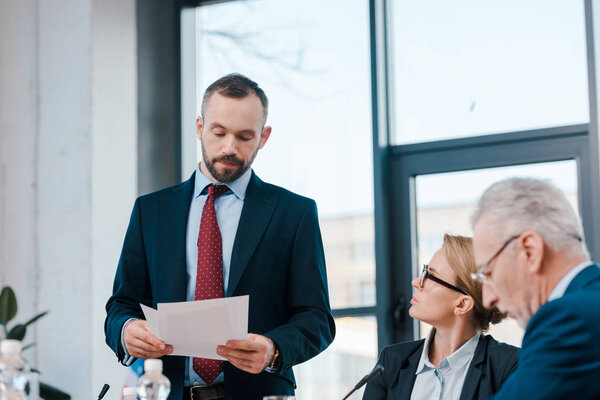 избирательный фокус бородатого дипломата, держащего бумаги рядом с представителями в очках
 