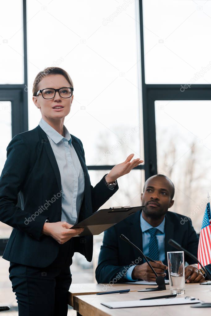 selective focus of attractive diplomat gesturing while talking near african american representative 