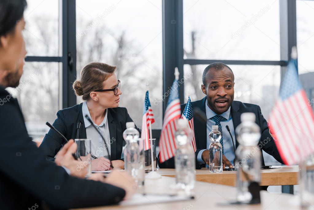 selective focus of attractive businesswoman looking at african american diplomat 