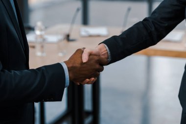 cropped view of businesswoman shaking hands with african american diplomat  clipart