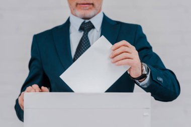 Tuğla duvarın yanında oy veren sakallı işadamı manzarası 