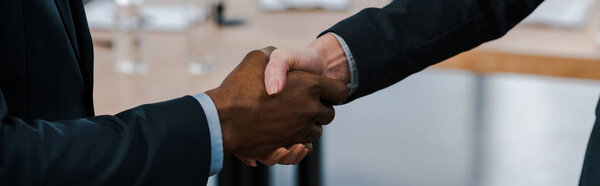 panoramic shot of businesswoman shaking hands with african american businessman 