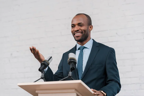 Fröhlicher Afrikanisch Amerikanischer Sprecher Gestikuliert Der Nähe Von Mikrofonen — Stockfoto