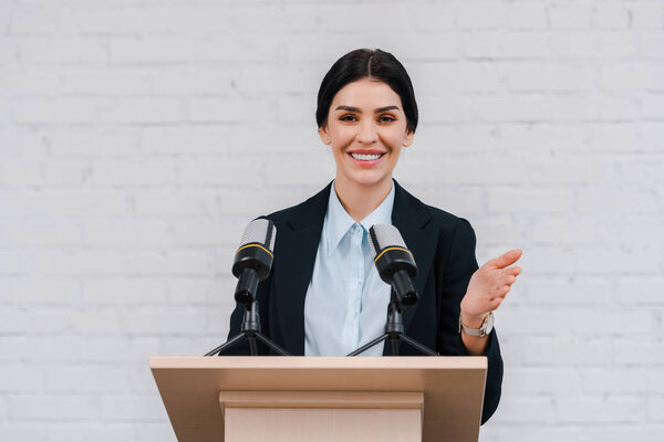 happy speaker gesturing and smiling near microphones 