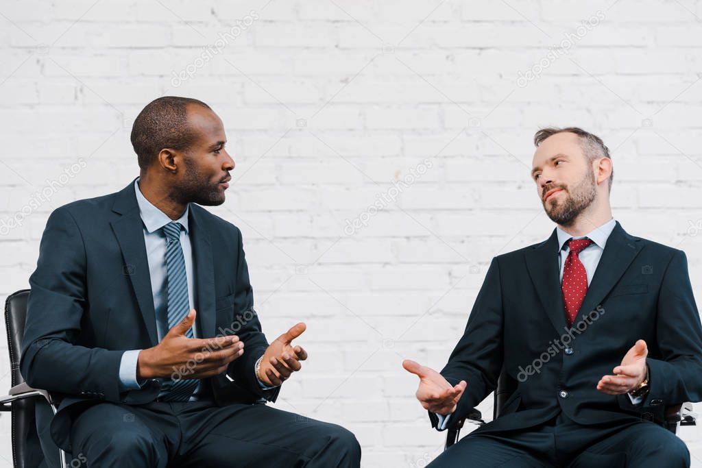 handsome african american businessman gesturing while looking at diplomat 