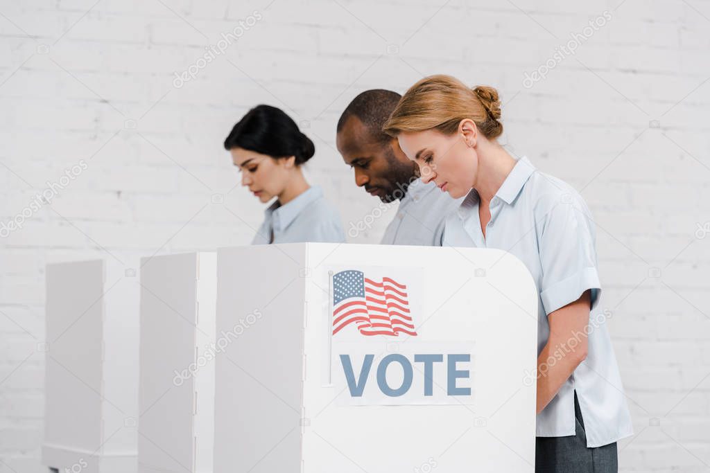 side view of women and african american man voting near vote lettering and brick wall 