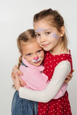 Kedi ağızlığı takan mutlu arkadaşlar ve sarılan yüzlerdeki çiçek resimleri beyaza izole edilmiş kameraya bakarken