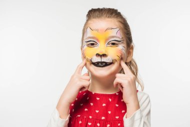 cheerful child with tiger muzzle painting on face touching face with fingers isolated on white clipart