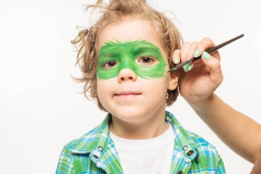 partial view of artist painting gecko mask on face of adorable boy isolated on white clipart