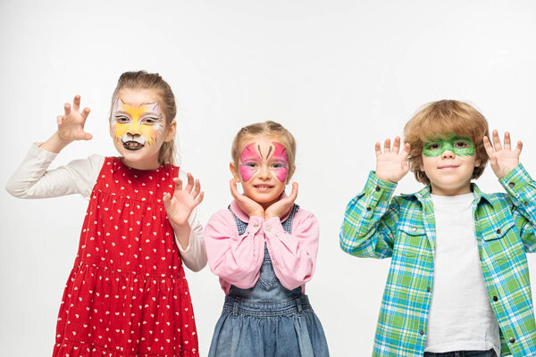 cheerful friends with colorful face paintings showing frightening gestures while looking at camera isolated on white